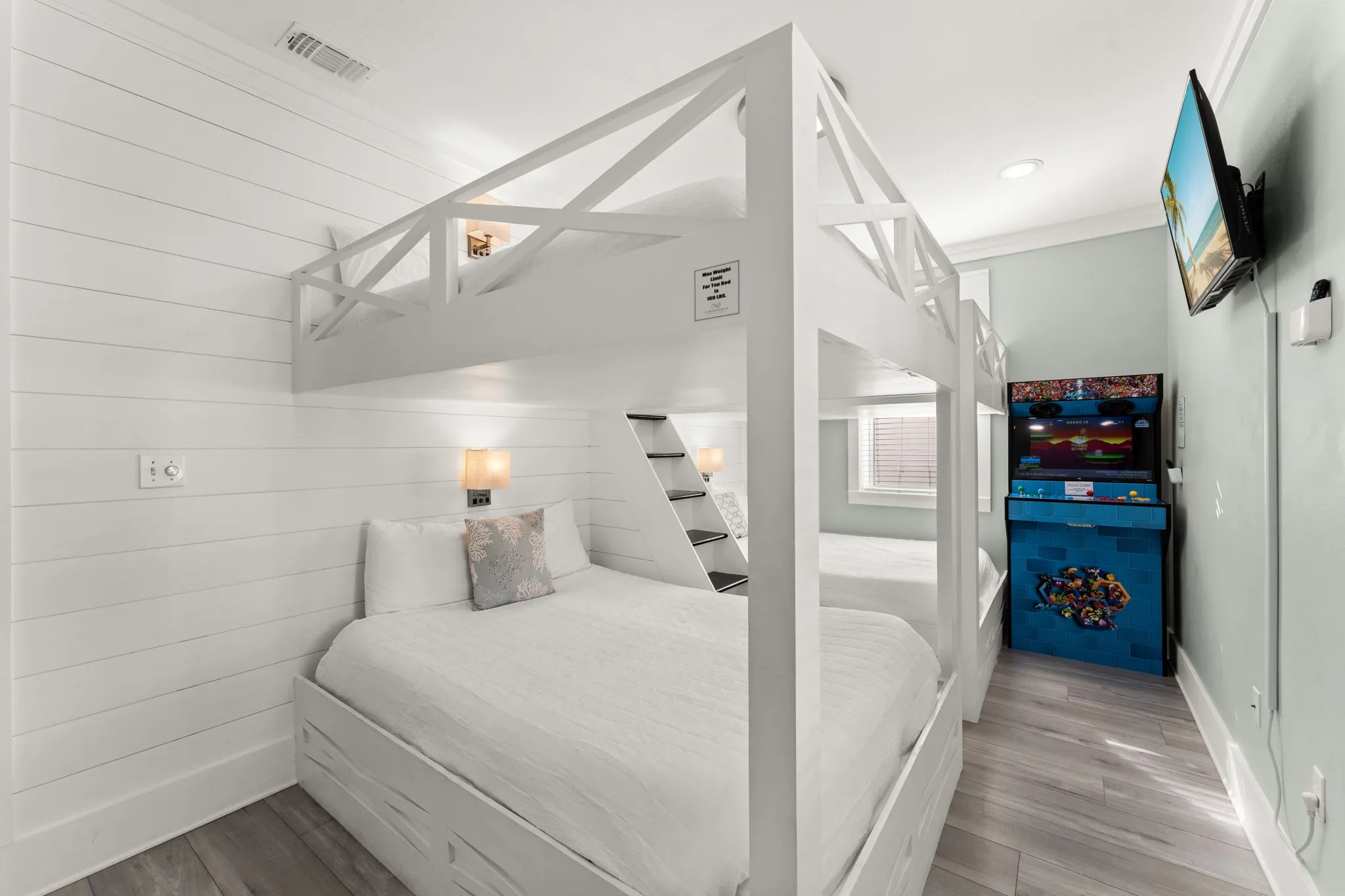 Custom queen-over-queen bunks with shiplap walls and arcade machine