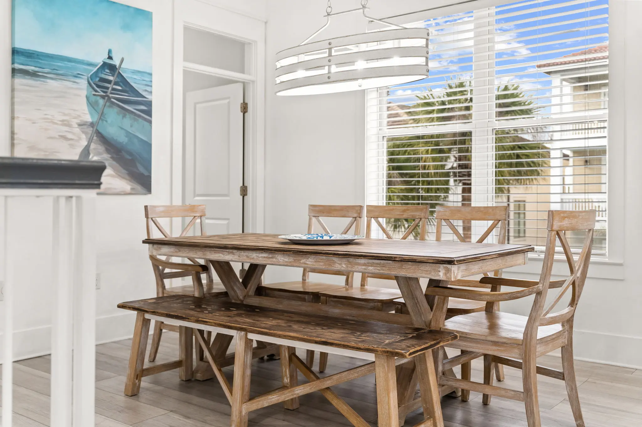 Farmhouse dining table with coastal boat art and chandelier