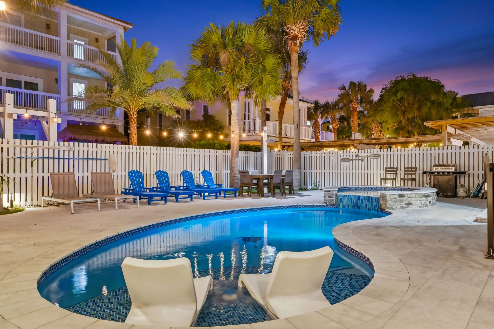 The Sandborne pool area at twilight with in-pool lounge chairs, spa, palm trees, and festoon lights